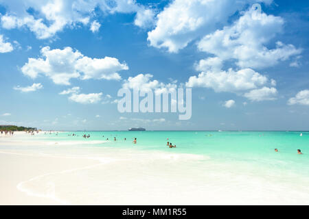 Eagle Beach, Aruba, Caribbean Sea in January 2018: tourists taking a bath in the turquoise waters or a stroll along the shoreline. Stock Photo
