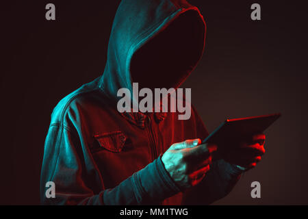 Hacker using tablet computer, red and blue lit low key image Stock Photo