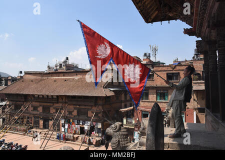 Bhaktapur, Nepal - March 23, 2018: Man waving a Nepalese flag on Nyatapola temple Stock Photo