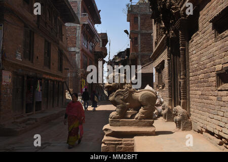 Bhaktapur, Nepal - March 23, 2018: Narrow street in the city and lion statue Stock Photo