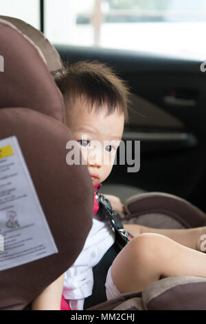 Portrait of cute toddler boy sitting in car seat. Stock Photo