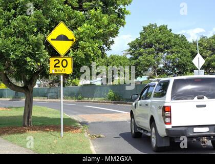 Moving traffic on 20 km speed limit street. Road sign post with 20 km per hour and speed bump Stock Photo