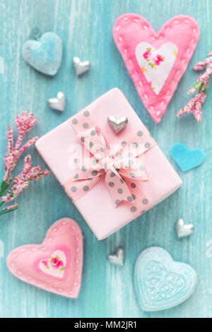 Valentine's Day concept with twrapped gift box and many different hearts on turquoise color wooden background Stock Photo