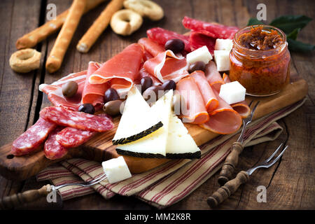 Cured meat and cheese platter of traditional Spanish tapas - chorizo, salsichon, jamon serrano, lomo and slices of goat cheese - served on wooden boar Stock Photo