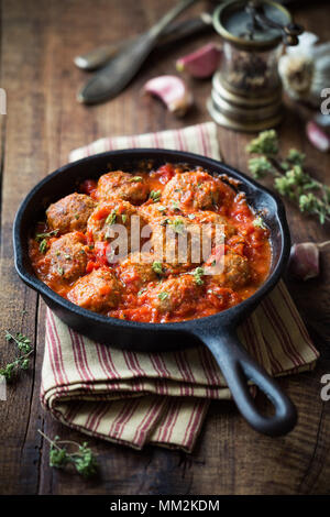 Meatballs in tomato sauce with dried oregano in a rustic vintage cast iron skillet Stock Photo