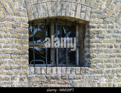 old window to renovate with bars on a yellow brick wall Stock Photo