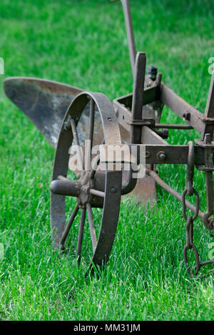 An old equestrian plow on green grass. The middle band of Russia.  Very rare ancient plow. Stock Photo