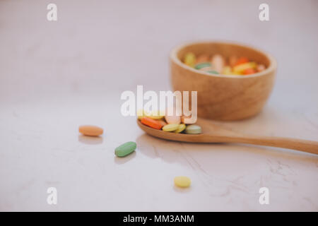 Assorted pharmaceutical medicine pills, tablets and capsules on wooden bowl Stock Photo