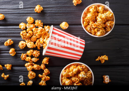 three striped boxes of sweet caramel popcorn close-up on wooden background. horizontal top view from above Stock Photo