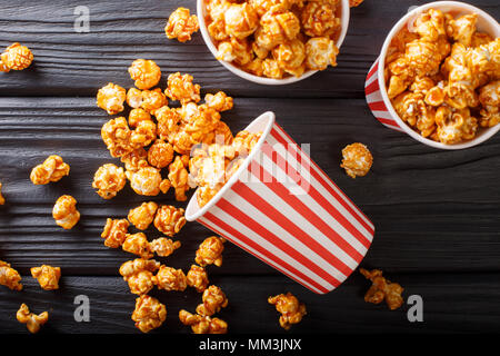Sweet caramel popcorn in paper cups close-up on the black table. horizontal top view from above Stock Photo