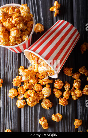 Sweet caramel popcorn in paper cups close-up on the black table. Vertical top view from above Stock Photo