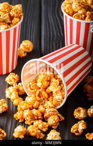 Sweet caramel popcorn in paper cups close-up on the black table. vertical Stock Photo