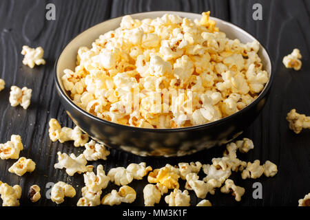 Cheddar cheese salted popcorn closeup in a  bowl on black table. vertical