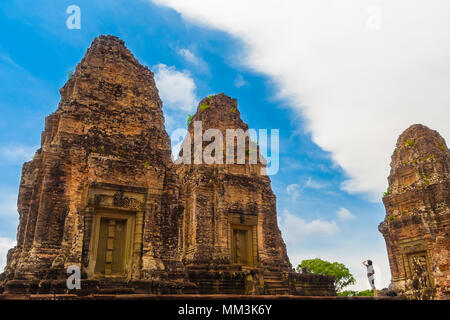 Great photo of a tourist looking up to two laterite brick towers of the inner sanctuary in Cambodia's East Mebon temple. Stock Photo