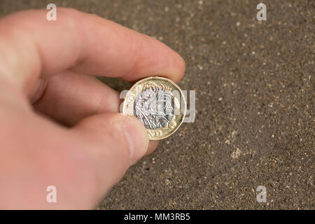 Posed picture of picking up a one pound coin from the ground. UK Stock Photo