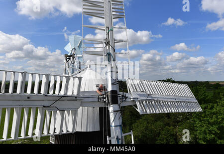Miller Dave Pearce adjust bolts from the storm hatch of Wicken Village windmill in Cambridgeshire as a new sail is fitted to the 19th century smock. Stock Photo