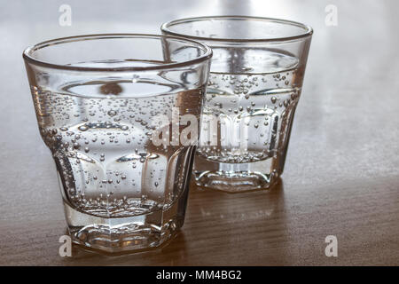 Two freshly poured glasses of sparkling water isolated on wood. Stock Photo