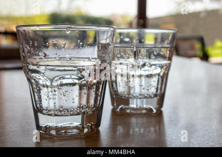 Two freshly poured glasses of sparkling water on wood table. Stock Photo