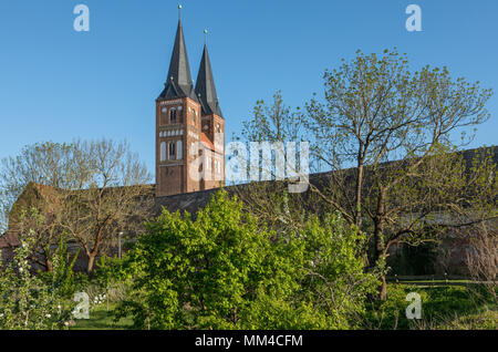 Jerichow Monastery with bell towers of collegiate church, Saxony-Anhalt, Germany. Orchard in foreground Stock Photo