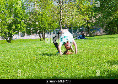 Young girl in the park practicing on grass in the background trees and people sitting on the ground under a tree Stock Photo