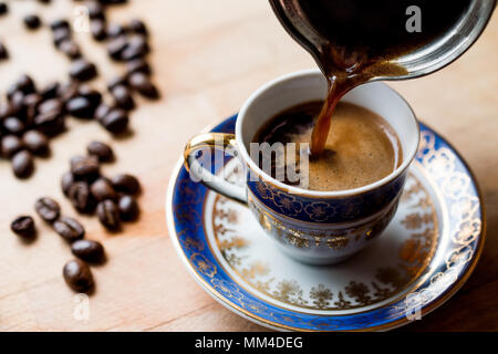 Pouring turkish coffee into traditional cup. Traditional Beverage. Stock Photo