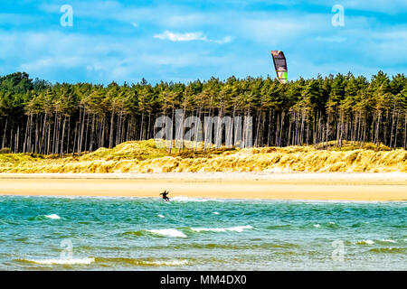 Kite flyer surfing at Newborough beach - Wales - United Kingdom Stock Photo