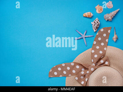 Straw  hat and seashells on blue background Stock Photo