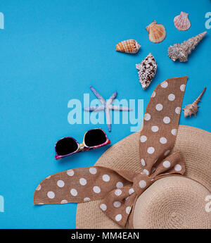 Straw  hat and seashells on blue background Stock Photo
