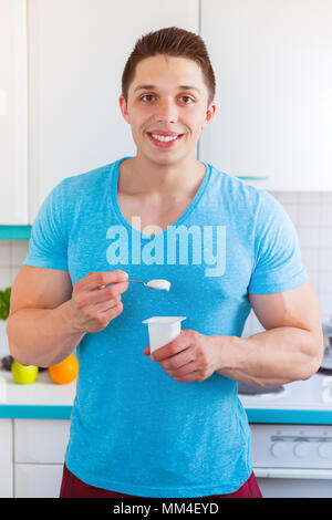 Healthy eating young man yogurt in the kitchen portrait format breakfast smiling Stock Photo