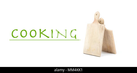 Two used wooden cutting boards isolated on white background with written sign Cooking. Green letters on white surface Stock Photo