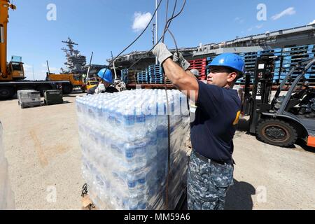 170907-N-YF329-0072 NORFOLK (Sept. 7, 2017) Airman Joshua Rowland, left, and Air Traffic Controller Airman Jonathan Tamez,  move cases of water on board the Nimitz-class aircraft carrier USS Abraham Lincoln (CVN 72) during a supply onload. Abraham Lincoln is moored in Norfolk after completing training while underway and stands ready to respond to the mission of the U.S. Navy. (U.S. Navy photo by Mass Communication Specialist 3rd Class Patrick D. Maher/Released) Stock Photo