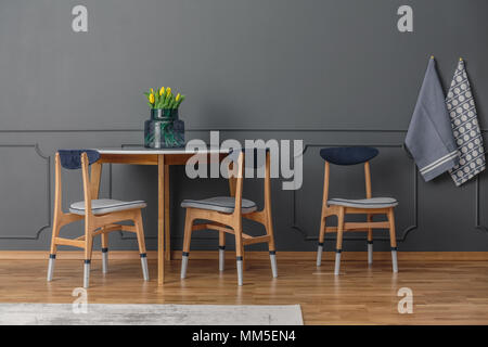 Grey wall with molding in a dining room interior with table and chairs Stock Photo
