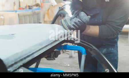 Man worker in car workshop polishing the car - preparing for painting Stock Photo