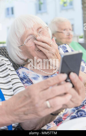 Senior woman looking at smartphone and laughing Stock Photo