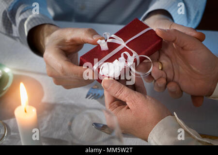 Romantic couple exchanging gift at candlelight dinner Stock Photo