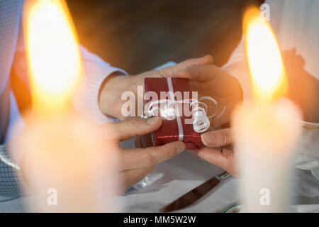 Romantic couple exchanging gift at candlelight dinner Stock Photo