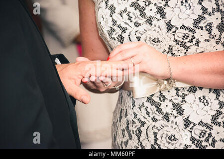 Wedding ceremony, bride putting ring on grooms finger Stock Photo