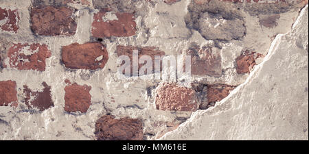 Old grungy red brick wall with damaged plaster banner background texture. Stock Photo