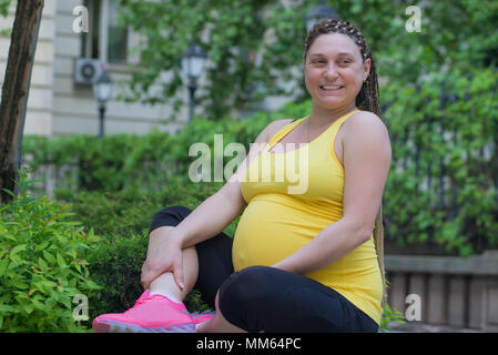 Happy smiling pregnant woman sitting outdoors, spring or summer time. Stock Photo