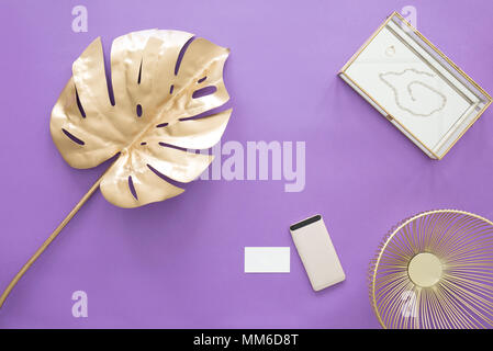 Golden leaf, phone, business card and metal bowl on a purple table Stock Photo