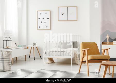 Minimalist framed posters on a white wall in a nordic style child's bedroom interior with designer decor and modern furniture