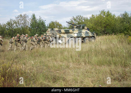 Ukrainian soldiers from the 1st Battalion, 95th Separate Airmobile Brigade take cover behind a BTR armored vehicle during a simulated ambush as part of Exercise Rapid Trident 2017 at the Yavoriv Combat Training Center on the International Peacekeeping and Security Center in Western Ukraine, on Sept. 11.    The 1-95th is training at the Yavoriv CTC taking part in Exercise Rapid Trident 2017 alongside 13 other nations in a show of partnership between Ukraine and NATO nations. Rapid Trident began on Sept. 11 and will take place until Sept. 23. During the exercise, troops will take part in trainin Stock Photo