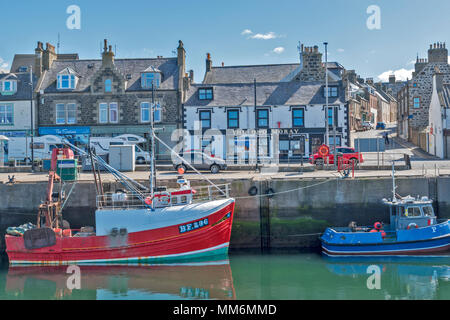 MACDUFF ABERDEENSHIRE SCOTLAND SHIPYARD OR BOATYARD BOATS IN THE HARBOUR ALONGSIDE THE MAIN ROAD AND SHOPS Stock Photo