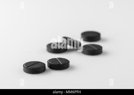several black medical activated charcoal pills on white background. Isolated Stock Photo