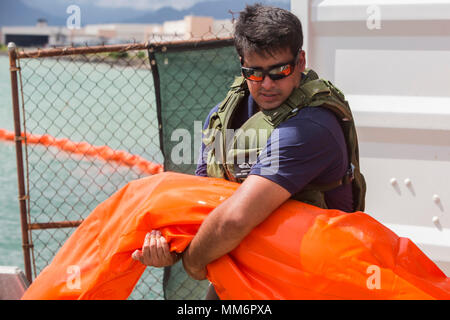 U.S. Navy Machinist’s Mate Third Class Jonathan Davis with Waterfront Operations, pulls in a floating barrier after a simulated oil spill at the marina aboard Marine Corps Base Hawaii (MCBH), Sept. 12, 2017. The training was part of the annual Anti-Terrorism Force Protection Exercise Lethal Breeze, which simulated a terrorist attack aboard MCBH, where a vessel was struck by explosives and leaked oil into Kaneohe Bay. (U.S. Marine Corps photo by Lance Cpl. Isabelo Tabanguil) Stock Photo