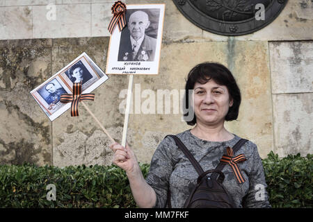 Athens, Greece. 9th May, 2018. A Russian woman who lives in Greece seen holding several old photographs during The Immortal Regiment march.Thousands of Russian citizens participated in the celebrations for the 73rd anniversary of the victory against fascism, which has been established as a Victory Day. With the military parade as well as the demonstration, the festive event took place across Russia, with citizens holding photos of their relatives who have either fought or been killed during the World War. Credit: Nikolas Joao Kokovlis/SOPA Images/ZUMA Wire/Alamy Live News Stock Photo