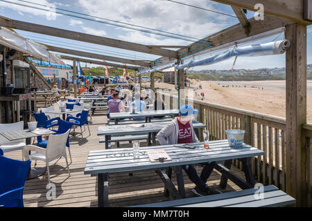 Holidaymakers relaxing on the terrace of the Fistral Beach Bar overlooking Fistral beach in Newquay Cornwall. Stock Photo