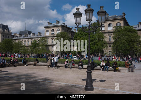 Tourists relax near Notre-Dame cathedral in the Place Jean-Paul II, Paris Stock Photo