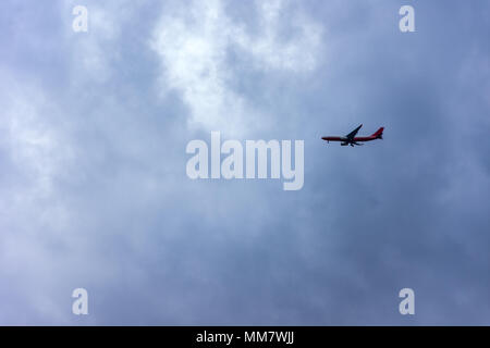 airplane flying in the cloudy and dark sky Stock Photo
