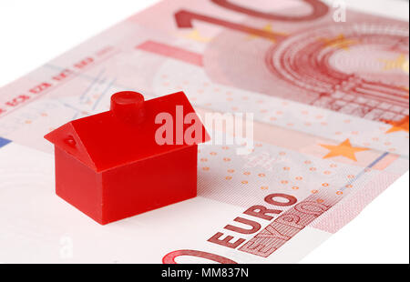 Red litle plastic house on a ten euro banknote on white background. Stock Photo